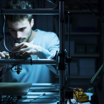 Young apprentice using a 3D printer machine